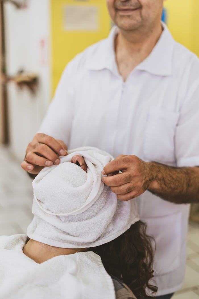 team-04 A barber performs a traditional grooming service by wrapping a towel over a client's face inside a barbershop.